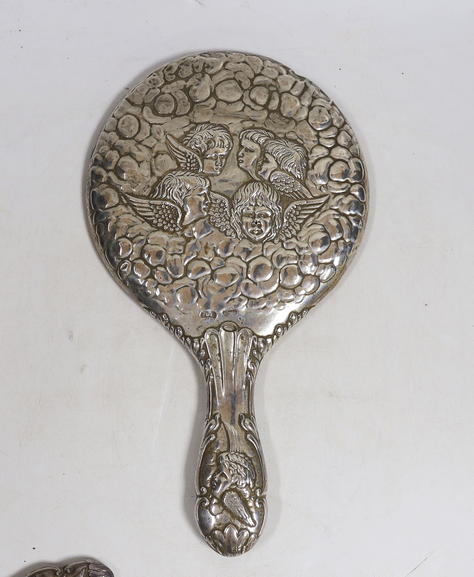 Two early 20th century repousse silver mounted hand mirrors with Reynold's Angels decoration, four silver mounted brushes and a comb.